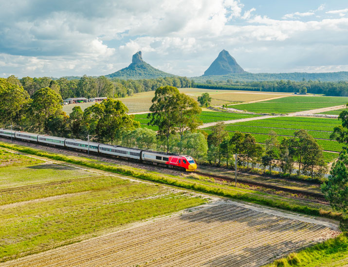 the Spirit of Queensland train travelling through  the Glasshouse Mountains