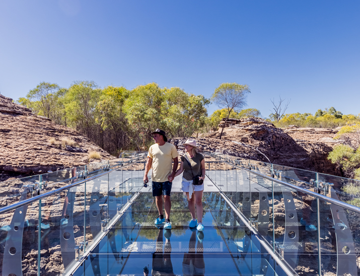 A couple walking over a glass bridge on Cobbold Gorge