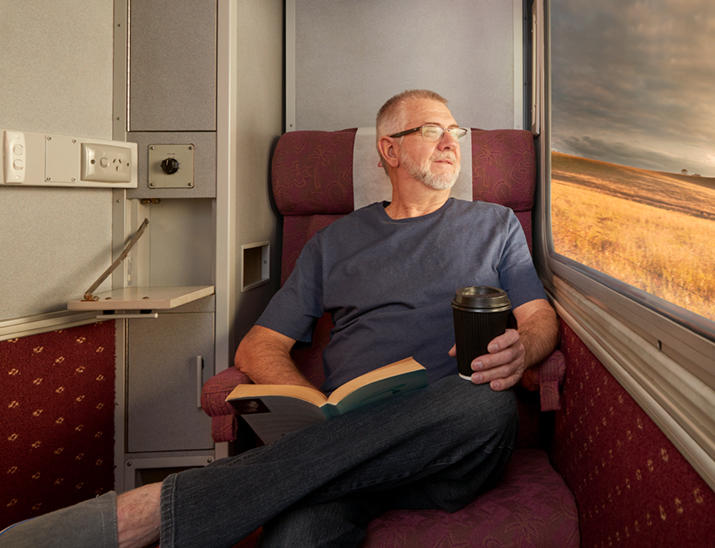 A customer sits enjoying a coffee in their Sleeper aboard Spirit of the Outback